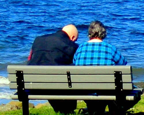 A man and woman sitting by the sea on a chair