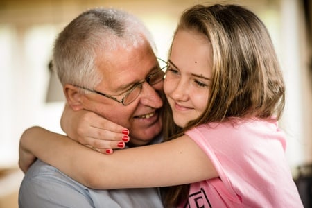 A little girl hugging an elderly man