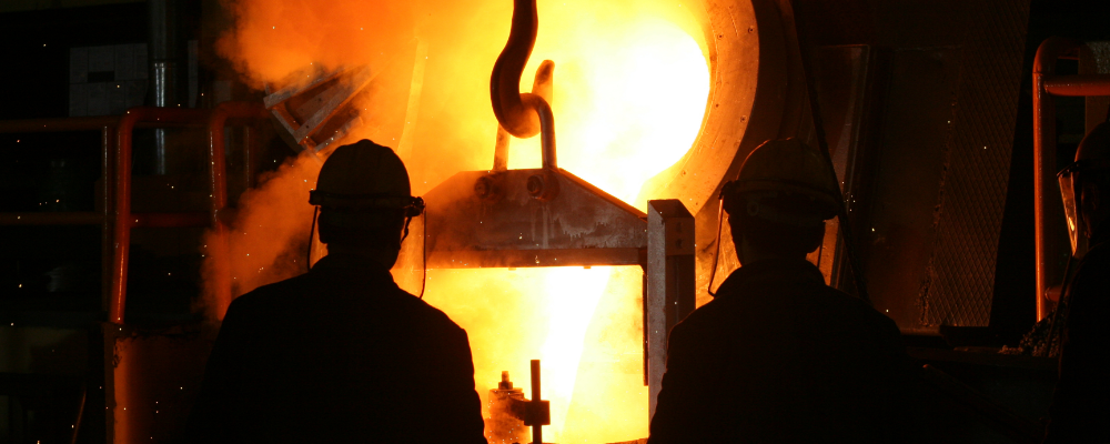 silhouettes of foundry workers watching molten metal pouring