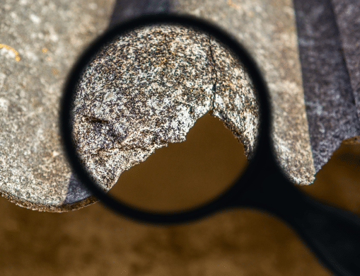 magnifying glass looking at asbestos fiber board